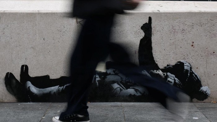 Sebuah mural baru yang diduga merupakan karya seniman anonim Banksy mencuri perhatian publik di Tottenham Court Road, London, Inggris, Selasa (22/12/2025). Mural tersebut langsung menyedot perhatian pejalan kaki dan pengguna jalan yang melintas di kawasan pusat kota London itu. REUTERS/Isabel Infantes