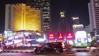 Gemerlap lampu dekoratif menerangi ikon pusat kota Jakarta, menciptakan suasana hangat dan meriah selama perayaan Natal 2025. 