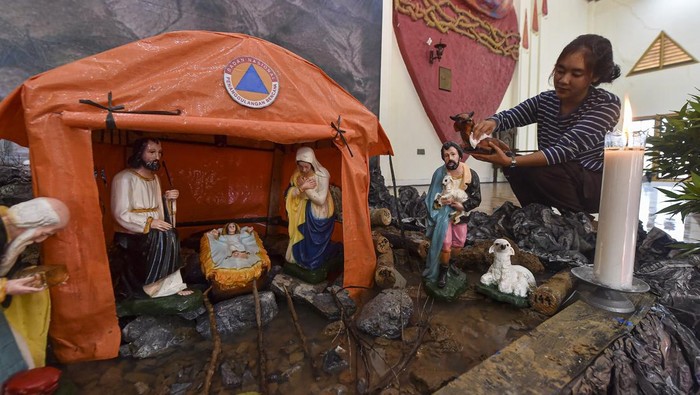 Umat Kristiani merapikan diorama tempat kelahiran Yesus di Gereja Katolik Santo Thomas, Desa Pandan Makmur, Tanjung Jabung Timur, Jambi, Selasa (23/12/2025). Perayaan Natal tahun 2025 di gereja tersebut diwarnai dengan ornamen bertema bencana alam guna memberikan dukungan morel dan bentuk solidaritas umat Kristiani setempat atas musibah yang terjadi di Aceh, Sumatera Utara, dan Sumatera Barat. ANTARA FOTO/Wahdi Septiawan/bar