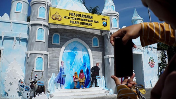 Pengendara melintas di depan Pos Pelayanan pengamanan Natal 2025 dan Tahun Baru 2026 bertema Frozen Disneyland di Kabupaten Jombang, Jawa Timur, Selasa (23/12/2025). Satuan Lalu Lintas Polres Jombang membangun pos pelayanan ramah keluarga tersebut dalam rangka menjaga keamanan selama libur Natal dan Tahun Baru 2026. ANTARA FOTO/Syaiful Arif/agr