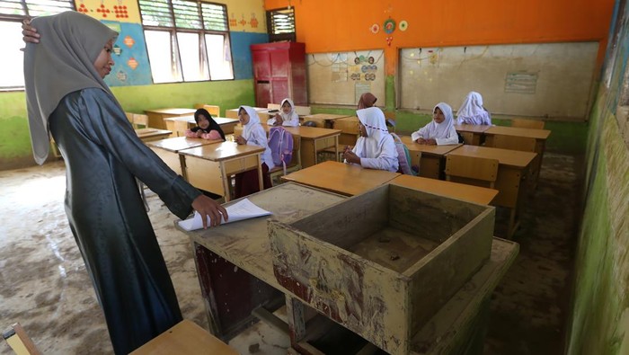 Pelajar menjemur Alquran dan buku pelajran yang tergenang banjir bandang di SD Negeri Seuneubok Johan, Ranto Peureulak, Aceh Timur, Aceh, Selasa (23/12/2025). Data sementara posko tanggap darurat bencana hidrometeorologi Aceh menyebutkan sebanyak 452 unit sekolah yang tersebar di 18 Kabupaten dan kota di Provinsi Aceh tergenang lumpur dan rusak akibat bencana banjir bandang akhir November 2025 yang sebagian kecilnya sudah memulai aktivitas belajar mengajar. ANTARA FOTO/Irwansyah Putra