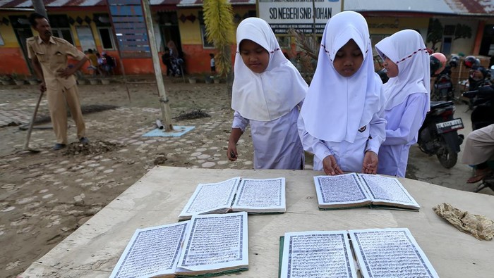 Pelajar menjemur Alquran dan buku pelajran yang tergenang banjir bandang di SD Negeri Seuneubok Johan, Ranto Peureulak, Aceh Timur, Aceh, Selasa (23/12/2025). Data sementara posko tanggap darurat bencana hidrometeorologi Aceh menyebutkan sebanyak 452 unit sekolah yang tersebar di 18 Kabupaten dan kota di Provinsi Aceh tergenang lumpur dan rusak akibat bencana banjir bandang akhir November 2025 yang sebagian kecilnya sudah memulai aktivitas belajar mengajar. ANTARA FOTO/Irwansyah Putra