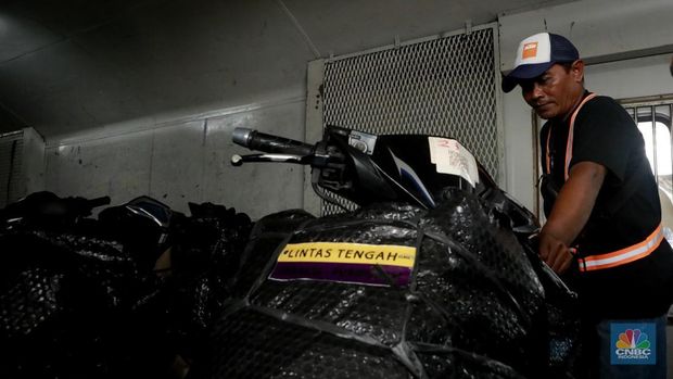 Pekerja merapikan motor peserta program motor gratis (Motis) KAI di gerbong Kereta Api Pasar Senen-Purwosari di Kawasan Stasiun Pasar Senen, Jakarta, Selasa, (23/12/2025). (CNBC Indonesia/Muhammad Sabki)
