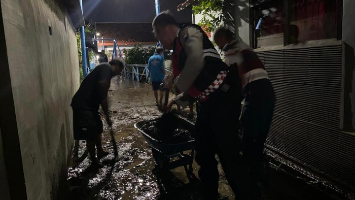 Anggota Polres Probolinggo membantu warga terdampak banjir luapan sungai di Dringu.