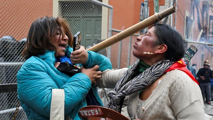 A miner scuffles with a woman who confronted demonstrators blocking the road as miners affiliated with Bolivia's main labor union protest following Bolivian government's decision to lift fuel subsidies, which have driven up diesel and gasoline prices, in La Paz, Bolivia, December 23, 2025. REUTERS/Claudia Morales     TPX IMAGES OF THE DAY