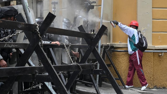 A demonstrator confronts police with spray as miners affiliated with Bolivia's main labor union protest following Bolivian government's decision to lift fuel subsidies, which have driven up diesel and gasoline prices, in La Paz, Bolivia, December 23, 2025. REUTERS/Claudia Morales