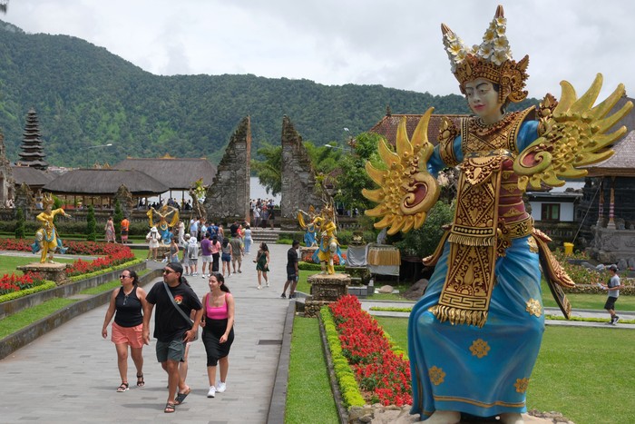 Wisatawan berjalan di dekat danau saat berkunjung di Daya Tarik Wisata (DTW) Ulun Danu Beratan, Tabanan, Bali, Rabu (24/12/2025). Pengelola objek wisata mencatat jumlah kunjungan wisatawan domestik maupun mancanegara pada liburan Natal mengalami peningkatan sejak empat hari terakhir yakni dari 1.100 orang menjadi 1.900 orang. ANTARA FOTO/Nyoman Hendra Wibowo/agr