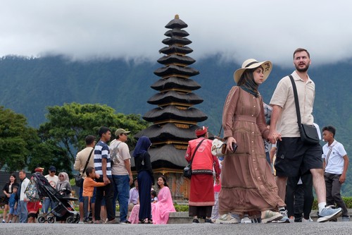 Wisatawan berjalan di dekat danau saat berkunjung di Daya Tarik Wisata (DTW) Ulun Danu Beratan, Tabanan, Bali, Rabu (24/12/2025). Pengelola objek wisata mencatat jumlah kunjungan wisatawan domestik maupun mancanegara pada liburan Natal mengalami peningkatan sejak empat hari terakhir yakni dari 1.100 orang menjadi 1.900 orang. ANTARA FOTO/Nyoman Hendra Wibowo/agr