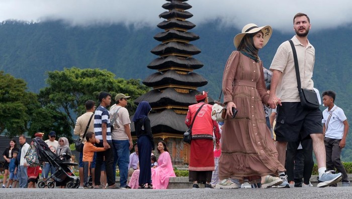 Wisatawan berjalan di dekat danau saat berkunjung di Daya Tarik Wisata (DTW) Ulun Danu Beratan, Tabanan, Bali, Rabu (24/12/2025). Pengelola objek wisata mencatat jumlah kunjungan wisatawan domestik maupun mancanegara pada liburan Natal mengalami peningkatan sejak empat hari terakhir yakni dari 1.100 orang menjadi 1.900 orang. ANTARA FOTO/Nyoman Hendra Wibowo/agr