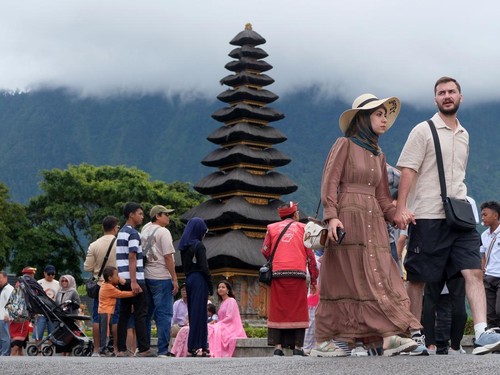Wisatawan berjalan di dekat danau saat berkunjung di Daya Tarik Wisata (DTW) Ulun Danu Beratan, Tabanan, Bali, Rabu (24/12/2025). Pengelola objek wisata mencatat jumlah kunjungan wisatawan domestik maupun mancanegara pada liburan Natal mengalami peningkatan sejak empat hari terakhir yakni dari 1.100 orang menjadi 1.900 orang. ANTARA FOTO/Nyoman Hendra Wibowo/agr