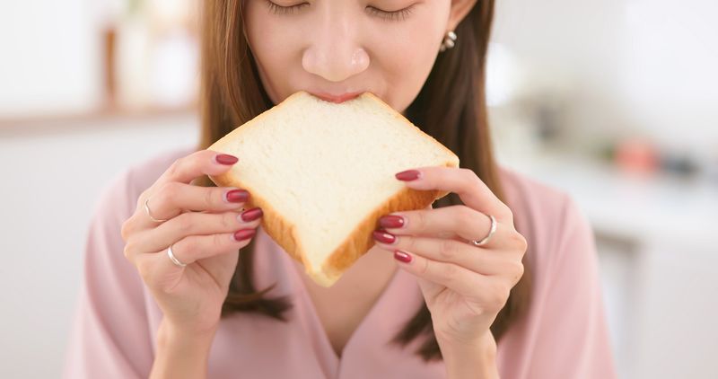 Closeup asian woman eat white toast at home - unhealthy food concept