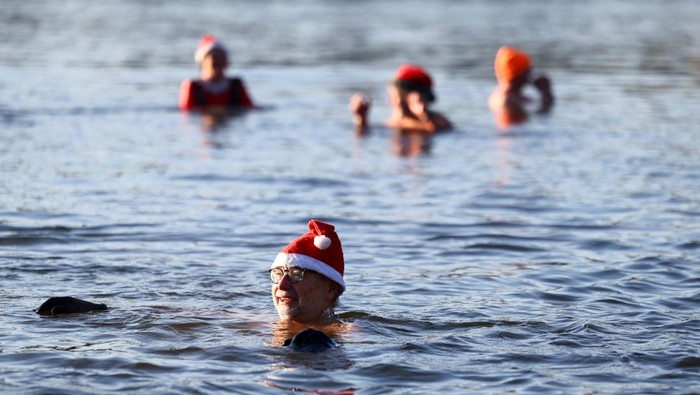 Perayaan Hari Natal 2025 di Berlin, Jerman, diwarnai dengan tradisi unik yang menarik perhatian publik. Para anggota klub perenang es Berliner Seehunde (Berlin Seals) kembali mengambil bagian dalam acara renang tradisional Natal dengan berendam di perairan dingin Danau Orankesee, Rabu (25/12/2025). REUTERS/Christian Mang