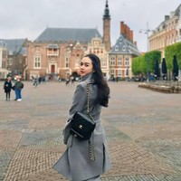 Tampil dengan gaya city chic, Aura Kasih mengenakan mantel panjang abu-abu bersiluet clean dan tailored. Dia tampak memakai backpack Chanel hitam dengan aksen rantai. Foto: Instagram/@aurakasih