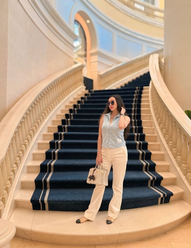 Bergaya santai tapi tetap mewah, Aura Kasih mengenakan kemeja sleeveless, celana putih dan flat shoes. Hermes Bikin hadir sebagai penambah gaya. Foto: Instagram/@aurakasih