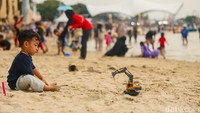 Seorang anak tampak menikmati pasir pantai sebagai ruang bermain terbuka, dari membuat istana pasir.