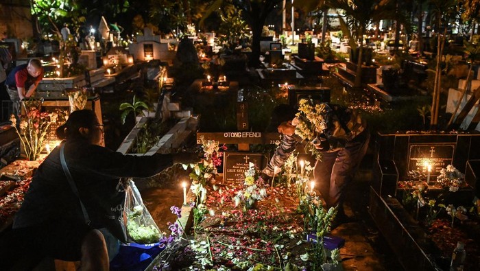 Malam Natal, Keturunan Portugis Kampung Tugu Ziarahi Makam Leluhur Warga keturunan Portugis menyalakan lilin dan menaruh bunga saat ziarah ke makam anggota keluarga saat malam Natal di kompleks Gereja Protestan Indonesia Barat (GPIB) Tugu, Semper Barat, Cilincing, Jakarta, Rabu (24/12/2025). Ziarah makam tersebut sudah menjadi tradisi keluarga keturunan Portugis di Kampung Tugu sebagai bentuk penghormatan dan mendoakan anggota keluarga yang telah wafat. ANTARA FOTO/Sulthony Hasanuddin