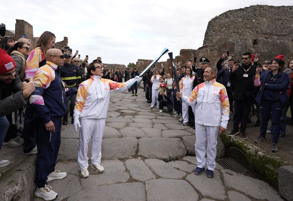 Olympics - 2026 Milano-Cortina Winter Olympics - 2026 Milano-Cortina Winter Olympics Torch Relay - Pompeii, Italy - December 22, 2025 Torchbearer actor Jackie Chan lights the torch with former Olympic gold medallist in fencing Sandro Cuomo during the torch relay REUTERS/Matteo Ciambelli
