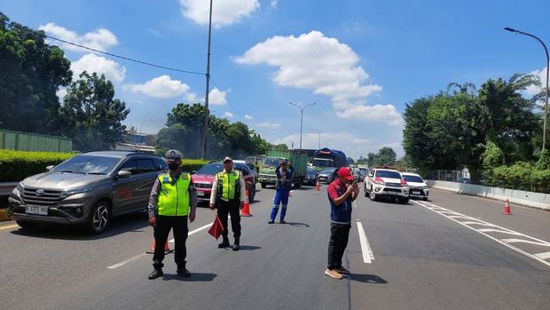 Polisi mengevakuasi truk kontainer terguling di Tol JORR dengan dua alat berat. (dok.TMC Polda Metro Jaya)