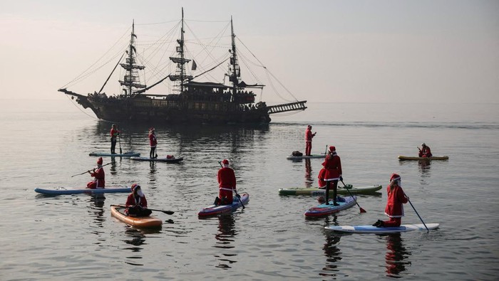 Members of the ThesSUP team( stand-up paddleboarding), wearing Santa Claus costumes, paddle off the seafront of Thessaloniki, Greece, December 21, 2025. REUTERS/Alexandros Avramidis