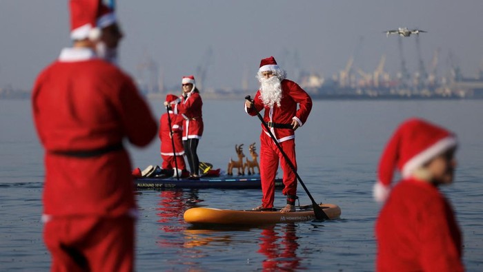 Members of the ThesSUP team( stand-up paddleboarding), wearing Santa Claus costumes, paddle off the seafront of Thessaloniki, Greece, December 21, 2025. REUTERS/Alexandros Avramidis