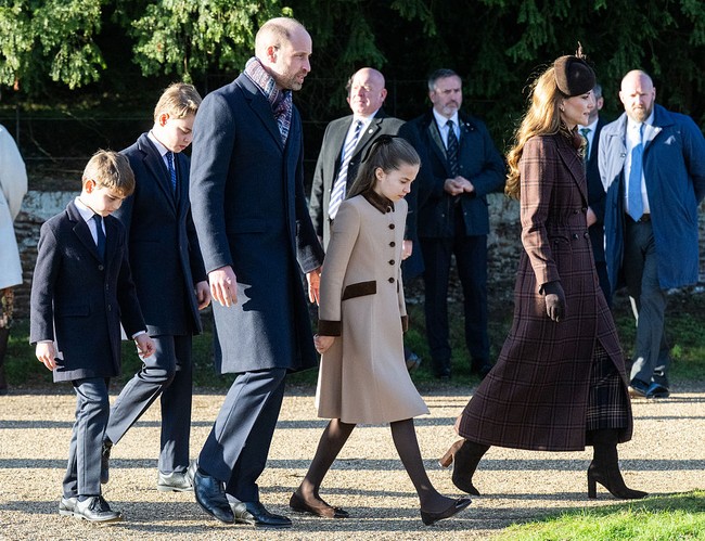 Berjalan bersama Pangeran William dan ketiga anak mereka, Kate Middleton mengenakan coatedress tartan cokelat Blazé Milano, rok liput Gucci, syal sutra cokelat-beige, dan sepatu bot cokelat tua. Foto: Samir Hussein/WireImage