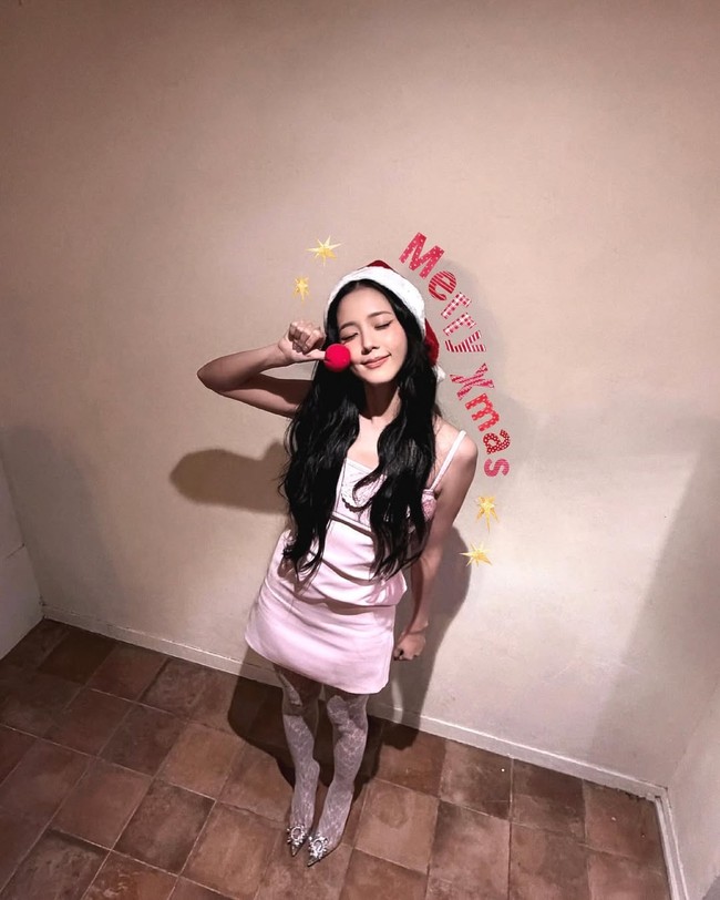 Jisoo menampilkan gaya manis, feminin dan penuh nuansa festive. Penyanyi sekaligus aktris ini mengenakan slip dress warna baby pink dipadu stocking lace putih. Foto: Instagram