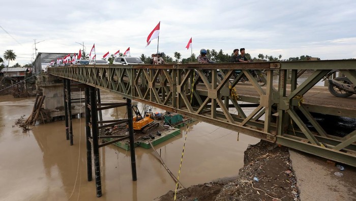 Warga dan kendaraan melewati jembatan darurat bailey Krueng Tingkeum yang baru selesai dibangun di Kuta Blang, Bireuen, Aceh, Sabtu (27/12/2025). Pemerintah bersama TNI/Polri telah menyelesaikan jembatan bailey Krueng Tingkeum, Kuta Blang  pascabencana banjir bandang yang merusak jembatan permanen akhir November lalu sepanjang 66 meter dengan kapasitas beban maksimal 30 ton sebagai upaya menghubungkan jalan negara Banda Aceh-Medan serta memperlancar distribusi logistik antar daerah. ANTARA FOTO/Irwansyah Putra/sgd