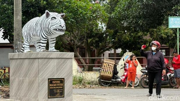 Sejumlah warga berfoto dengan patung Macan Putih di Kediri yang viral karena bentuknya lucu.