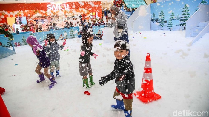 Sejumlah pegunjung bermain salju buatan di wahana Magical Chirstmas Snowy Celebration di Mal Artha Gading, Jakarta Utara, Sabtu (27/12/2025). Suasana pusat perbelanjaan berubah menjadi layaknya negeri musim dingin dengan hamparan salju putih, dekorasi pohon Natal berukuran besar, serta ornamen khas akhir tahun yang menghiasi hampir seluruh area wahana.
