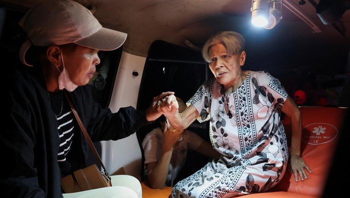 Local people rescue an elderly woman during a fire at Werdha Damai retirement home in Manado, North Sulawesi Province, Indonesia, December 28, 2025. REUTERS/Yegar Sahaduta Mangiri