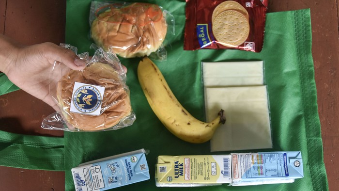 Siswa memperlihatkan menu Makan Bergizi Gratis (MBG) di SDN 1 Gunung Lipung, Kota Tasikmalaya, Jawa Barat, Senin (29/12/2025). Satuan Pelayanan Pemenuhan Gizi (SPPG) tetap menyalurkan bantuan MBG selama tiga hari berupa susu, buah, roti, biskuit, dan