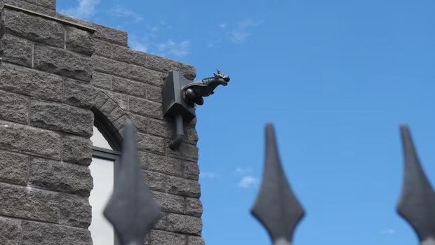 Patung-patung gargoyle hasil cetak 3D tersebar di sekitar bagian luar rumah.