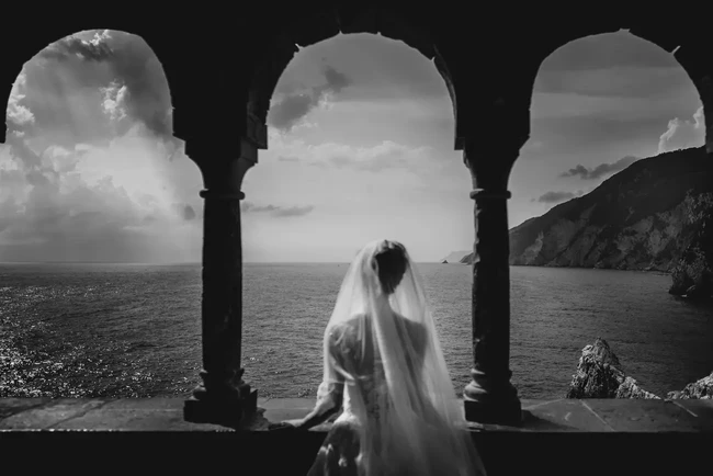 Alessandro Biggi memenangkan kategori Epic Location lewat foto yang diambil di Gereja San Pietro, Porto Venere, Italia. “Sang pengantin, dengan keanggunannya, berdiri diam menghadap keabadian, seolah terserap oleh puisi laut yang terbentang di balik pilar-pilar kuno—saksi bisu dari tak terhitung kisah, cinta, dan legenda,” tulis Biggi sang fotografer. Foto: Dok. iwpoty.com