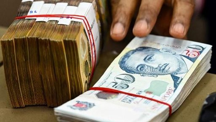 A staff counts packs of Singapore and Australian dollar currency notes at a money changer booth at Raffles Place financial business district in Singapore on October 6, 2022. (Photo by Roslan RAHMAN / AFP)