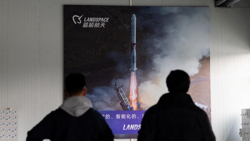 Two men walk next to a banner depicting rocket launch by China’s private rocket company LandSpace, at its factory in Huzhou, Zhejiang province, China, December 17, 2025. REUTERS/Maxim Shemetov