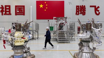 Seorang karyawan berjalan di samping mesin roket di aula perakitan dengan bendera nasional China terpampang di dinding sebagai latar belakang. Namun bulan ini media pemerintah secara luas meliput dua upaya gagal pertama China dalam memulihkan roket yang dapat digunakan kembali, dengan peluncuran kedua berasal dari perusahaan milik negara, hanya tiga minggu setelah peluncuran perdana roket yang dapat digunakan kembali Zhuque-3 milik LandSpace. Foto: REUTERS/Maxim Shemetov
