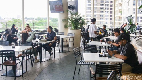 Pengunjung bekerja menggunakan komputer jinjing saat penerapan kebijakan Work From Anywhere di Pondok Indah Mall, Jakarta, Senin (29/12/2025).