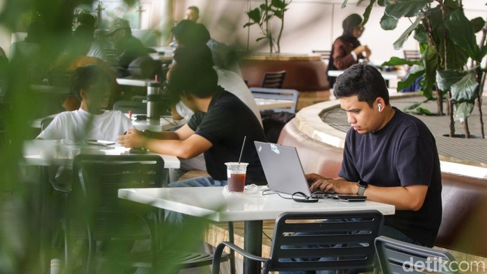Pengunjung bekerja menggunakan komputer jinjing saat penerapan kebijakan Work From Anywhere di Pondok Indah Mall, Jakarta, Senin (29/12/2025).