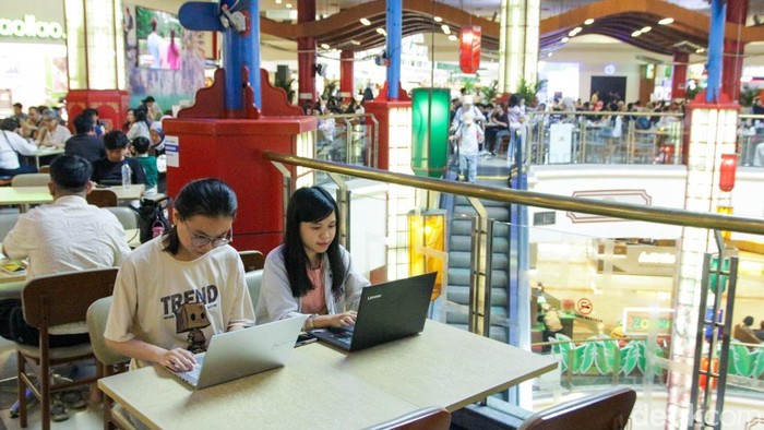 Pengunjung bekerja menggunakan komputer jinjing saat penerapan kebijakan Work From Anywhere di Pondok Indah Mall, Jakarta, Senin (29/12/2025).