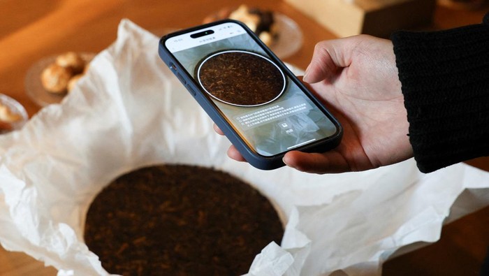 Eric Ma, founder and CEO of Teaken, scans a tea cake with the smartphone application at Bei Teahouse in Shanghai, China, December 15, 2025. REUTERS/Go Nakamura