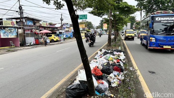 Tumpukan sampah berada di pembatas jalan di kawasan Kertapati, Palembang