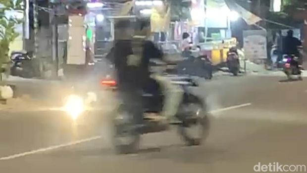 Pengendara motor menghindari petasan di tengah jalan di Makassar.