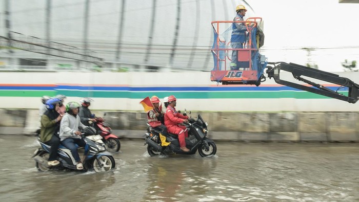 Pekerja proyek menaiki alat berat saat melintasi banjir rob di Jalan R.E Martadinata, Tanjung Priok, Jakarta Utara, Jumat (2/1/2026). BPBD DKI Jakarta mencatat ketinggian air banjir rob mencapai sekitar 15 cm akibat pasang maksimum air laut yang bertepatan dengan fase bulan purnama dan diprediksi berlangsung hingga 7 Januari 2026 di pesisir Jakarta. ANTARA FOTO/Fakhri Hermansyah/YU