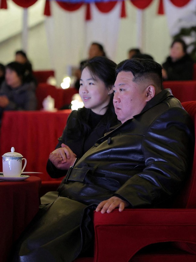 Salah satu momen yang paling mencuri perhatian terjadi saat perayaan Tahun Baru 2026 di Pyongyang. Ketika Kim Jong-un menepuk kursi di sampingnya, Kim Ju-ae menghampiri lalu mencium pipi sang ayah di hadapan para pejabat dan masyarakat. Bagi sejumlah analis, adegan tersebut bukan sekadar bentuk kasih sayang antara ayah dan anak, namun bagian dari rangkaian simbol yang membangun citra Kim Ju-ae sebagai figur penting dalam suksesi kepemimpinan Korea Utara. Foto: via REUTERS/KCNA