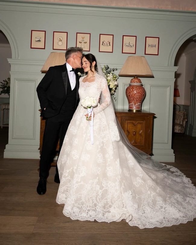 Untuk pesta resepsi di malam hari, Holly memilih gaun pengantin ibunya dari tahun 1996 yang membuat sang ibu semakin terharu di momen bahagia itu. “Gaun itu indah: sutra dengan garis leher V dan mutiara di sekelilingnya. Aku mencobanya dan pas sekali, tidak perlu diubah sama sekali,”  Foto: Instagram @hollyramsaypeaty/ @JasonLloydEvans.