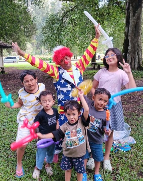 Muh Fakih Santoso (68), eks pemain Srimuat Surabaya, menghibur anak-anak dengan menyamar menjadi badut di Kebun Raya Bali. (Firizqi Irwan/detiBali)