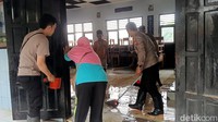 Sejumlah guru dan polisi setempat juga turut membantu membersihkan lumpur sisa banjir yang masuk ke kelas.