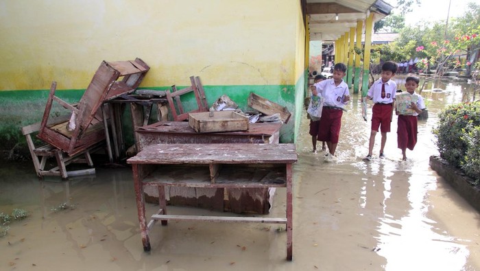 Siswa berusaha menerobos banjir menggunakan motor di Kelurahan Pekan Tanjung Pura, Kabupaten Langkat, Sumatera Utara, Senin (5/1/2026). Bencana banjir pada 27 Desember 2025 yang mengakibatkan 13 warga meninggal di wilayah tersebut belum surut dan masih menggenangi sejumlah rumah warga. ANTARA FOTO/Yudi Manar