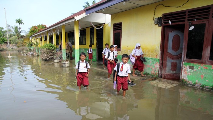 Siswa berusaha menerobos banjir menggunakan motor di Kelurahan Pekan Tanjung Pura, Kabupaten Langkat, Sumatera Utara, Senin (5/1/2026). Bencana banjir pada 27 Desember 2025 yang mengakibatkan 13 warga meninggal di wilayah tersebut belum surut dan masih menggenangi sejumlah rumah warga. ANTARA FOTO/Yudi Manar