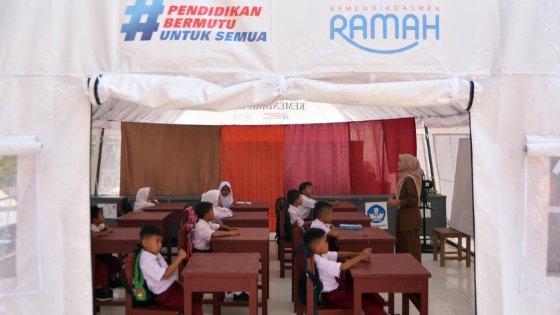 Sejumlah siswa mengikuti kegiatan belajar pada hari pertama sekolah di bawah tenda, di SDN 05 Batang Anai, Padang Pariaman, Sumatera Barat, Senin (5/1/2026). Sekolah yang hancur akibat banjir bandang bulan lalu itu tetap menjalankan kegiatan belajar - mengajar di bawah tenda bantuan Kemendikdasmen untuk dua kelas, ditambah bangunan kayu sementara untuk empat kelas.. ANTARA FOTO/Iggoy el Fitra
